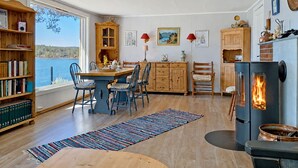 A cozy interior with a dining area, bookshelves, a fireplace, and a view of the outdoors. - Vacation home Ogge by Interhome (Vatnestrøm)