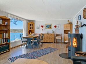 Een gezellig interieur met een eethoek, boekenkasten, een open haard en uitzicht op het landschap.