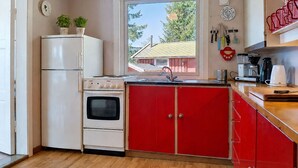 A compact kitchen with a refrigerator, oven, and red cabinets. - Vacation home Ogge by Interhome (Vatnestrøm)