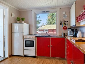 Una cocina compacta con refrigerador, horno y armarios rojos.