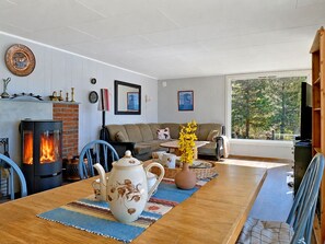 Een gezellige woonkamer met een open haard, een bank en een eettafel met waterkoker en theepot.