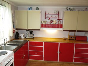 Geladeira, fogão, talheres/pratos/utensílios de cozinha, mesas de jantar