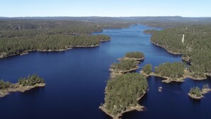Une vaste étendue d’eau entourée d’une forêt dense, parsemée de plusieurs petites îles et surplombée d’un ciel dégagé.
