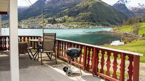 A balcony with a view of a lake and mountains, a grill, and outdoor furniture. - Naustvollen by Interhome (Balestrand)
