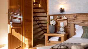 Eine Holztreppe führt zu einem Schlafzimmer mit einem Bett, einem Nachttisch und einer Wandleuchte.