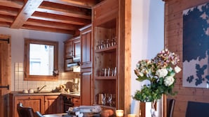 Eine rustikale Küche mit Holzsäulen, einem Esstisch mit Stühlen und einer Vase mit Blumen.