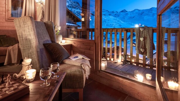 Ein gemütliches Holzblockhaus-Interieur mit Blick auf schneebedeckte Berge.