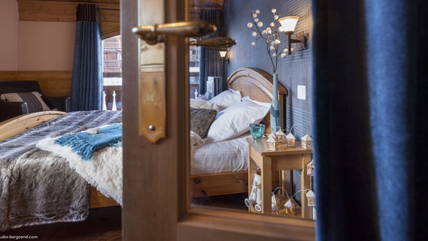 A cozy bedroom with a wooden bed, a nightstand with a lamp, and a view of a balcony.