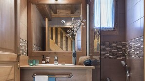 A bathroom with wooden cabinetry, a glass shower enclosure, and a mirror reflecting the room.