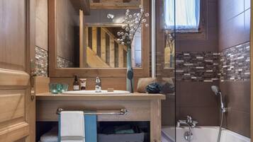 Une salle de bain avec des meubles en bois, une douche en verre et un miroir qui reflète la pièce.