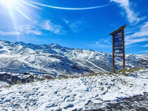 Eine verschneite Berglandschaft mit einem hölzernen Wegweiser, der einen Wanderweg zeigt.