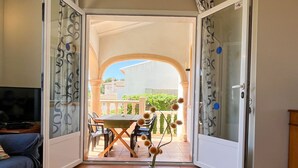 An open door leading to a balcony with a table, chairs, and a vase with dried flowers. - Lavanda by Interhome (Jávea)
