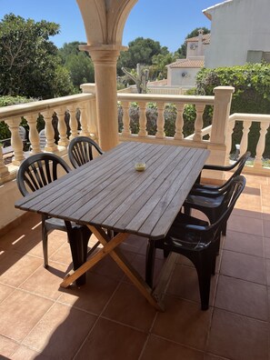 A wooden table with two chairs on a tiled patio with a balustrade. - Lavanda by Interhome (Jávea)