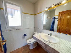 A bathroom with white tiled walls, a marble sink, a toilet, and a window. - Lavanda by Interhome (Jávea)