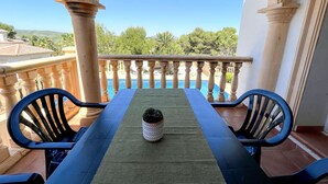 A balcony with a view of a swimming pool and greenery.
