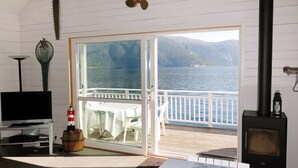 Una stanza con TV, tavolo, lavagna e vista su un lago e montagne.