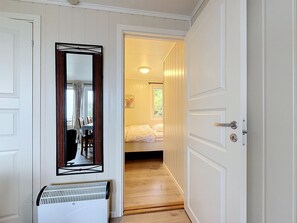 Un pasillo que conduce a un dormitorio con una cama, un radiador y un espejo en la pared.