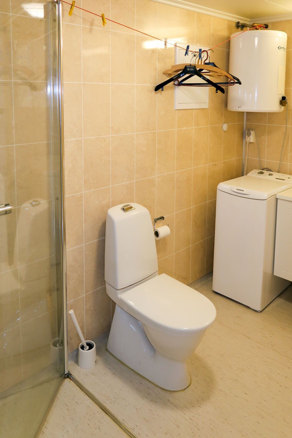 A bathroom with a toilet, a shower, and a washing machine.