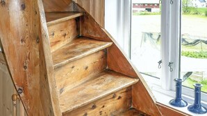 Un escalier en bois offrant une vue sur l’extérieur par une fenêtre.
