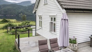Une maison blanche dotée d’une terrasse, d’une pergola et offrant une vue sur un lac et des montagnes.