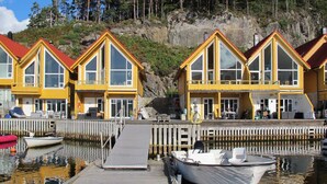 A row of yellow buildings with large windows, a wooden dock, and boats.