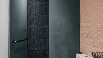 Un baño moderno con cabina de ducha de vidrio, inodoro blanco y tocador de madera.