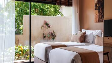 A hotel room with two beds, a large window with a view of greenery, and a wall-mounted TV.