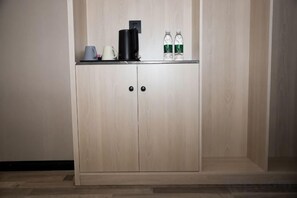 A wooden wardrobe with two doors, a flat surface on top with a coffee maker, a kettle, and two bottles. - Star Sky Hotel (Pingjiang)