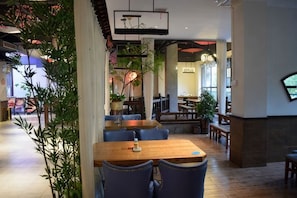 A restaurant interior with tables, chairs, and plants. - Star Sky Hotel (Pingjiang)