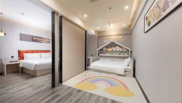 A modern bedroom with a bed, bedside table, and a small play area with a rainbow rug.