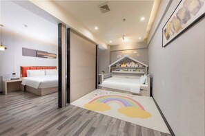 A modern bedroom with a bed, bedside table, and a small play area with a rainbow rug.