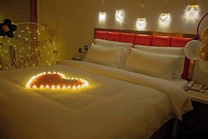 A hotel room with a bed, bedside table, lamp, and decorative wall lights. - Star Sky Hotel (Pingjiang)