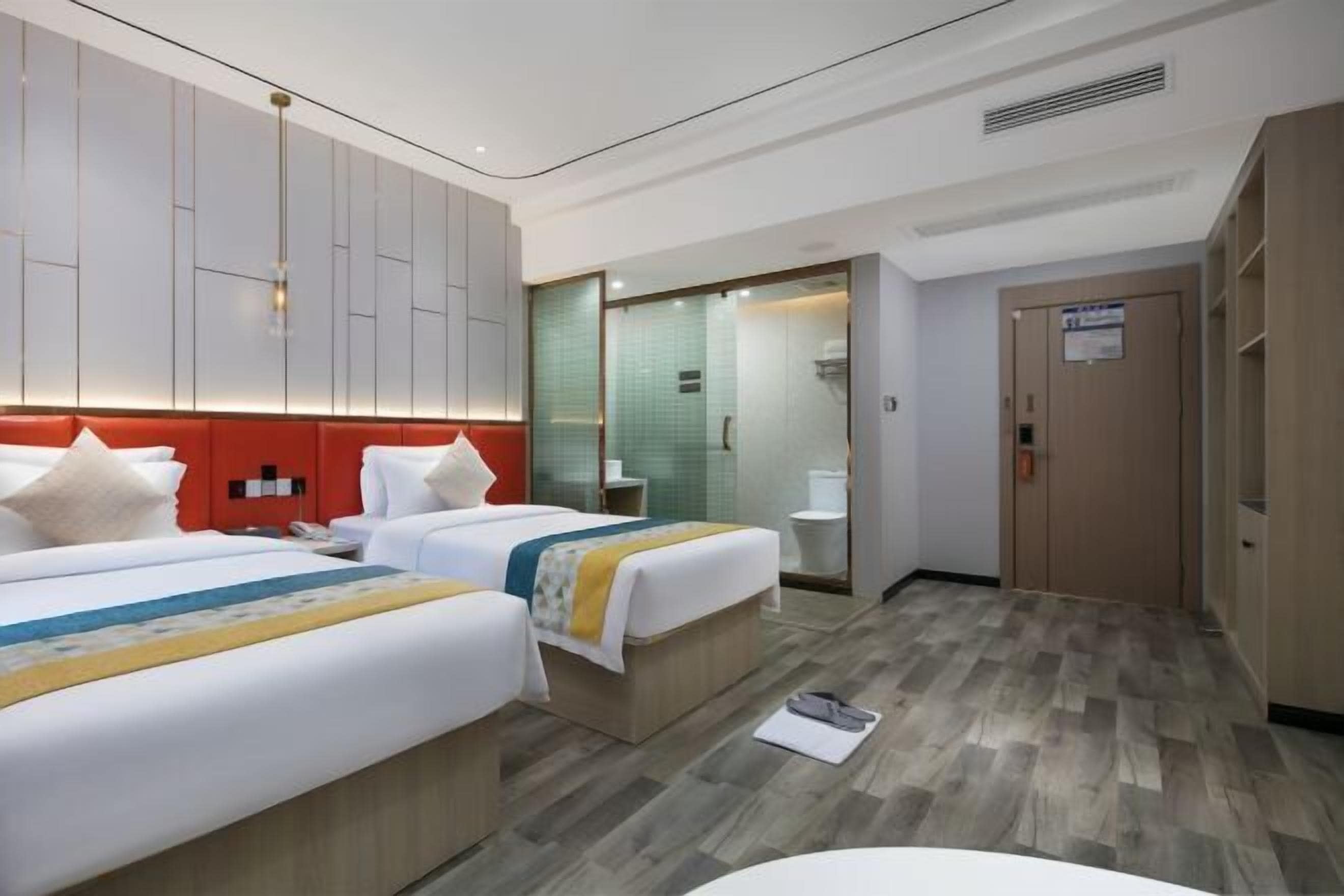 A hotel room with two beds, a bathroom, and a wardrobe.