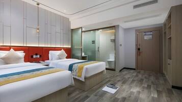 A hotel room with two beds, a bathroom, and a wardrobe.