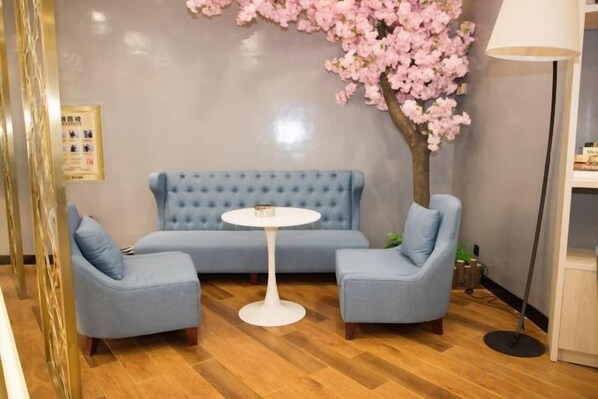 A room with a blue sofa set, a round table, and a cherry blossom tree. - Star Sky Hotel (Pingjiang)