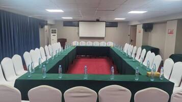 A conference room with a long table, chairs, and a projector screen.