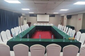 A conference room with a long table, chairs, and a projector screen.