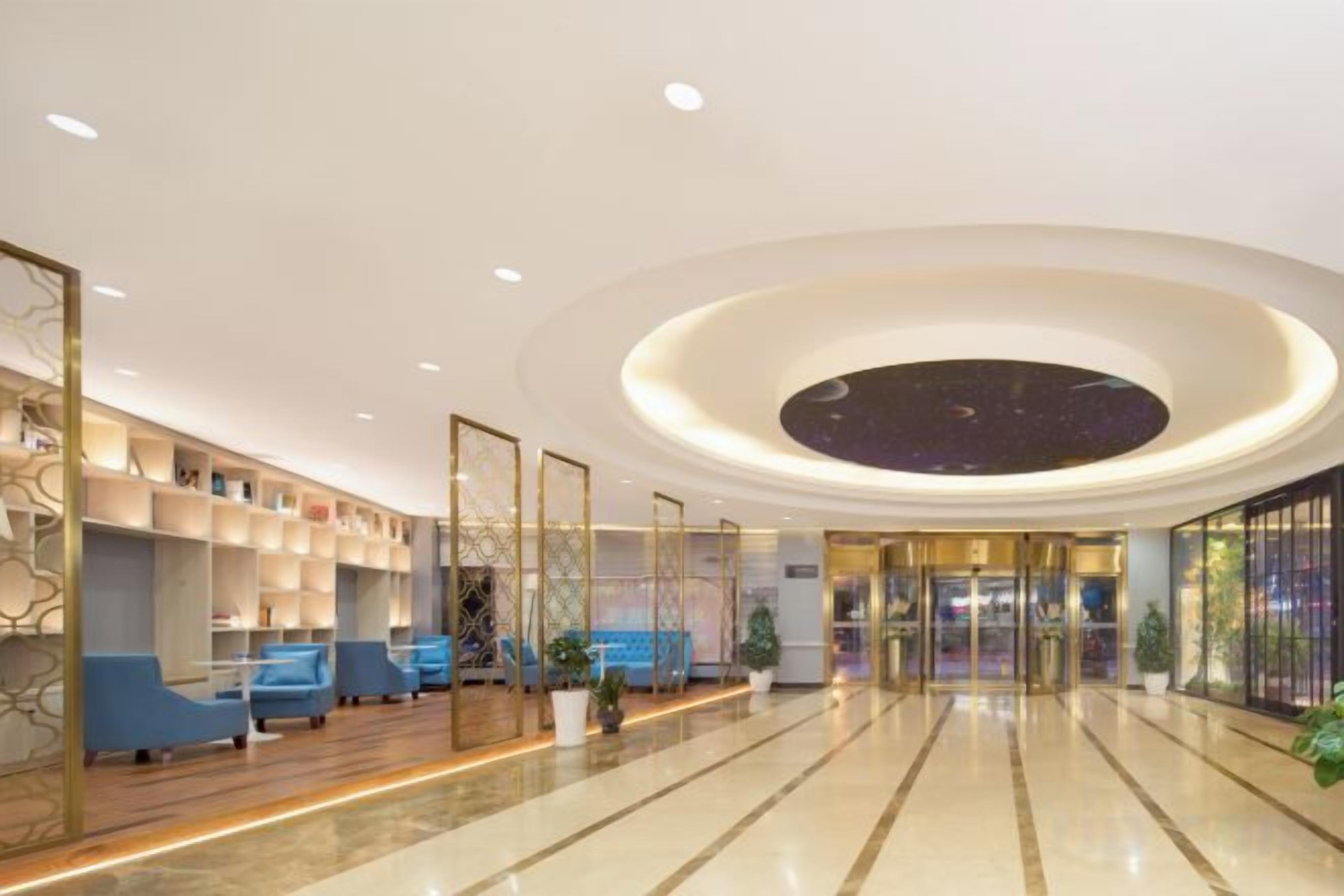 A hotel lobby with a circular ceiling design, seating area, and a reception desk.