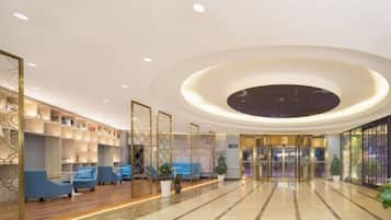 A hotel lobby with a circular ceiling design, seating area, and a reception desk.