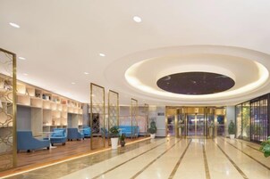 Eine Hotellobby mit kreisförmigem Deckenstil, einer Sitzecke und einer Rezeption.