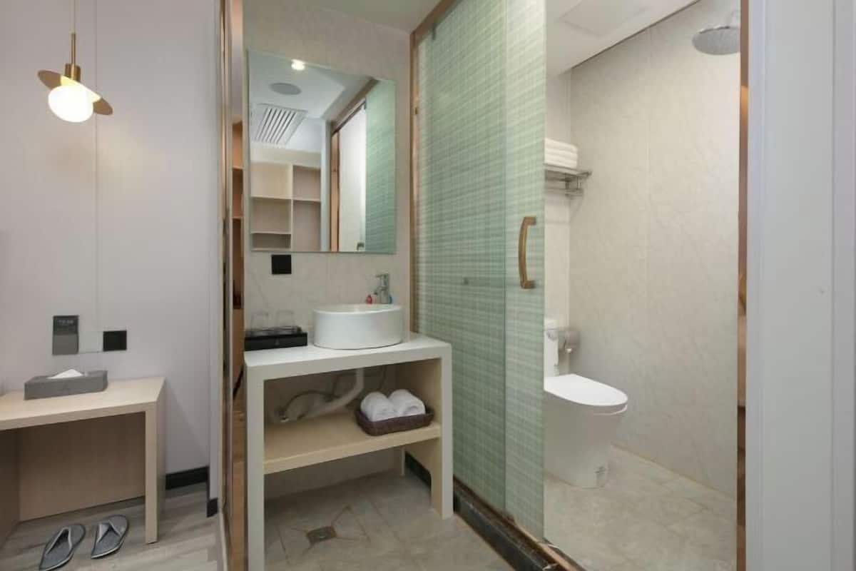 A modern bathroom with a sink, mirror, and shower.