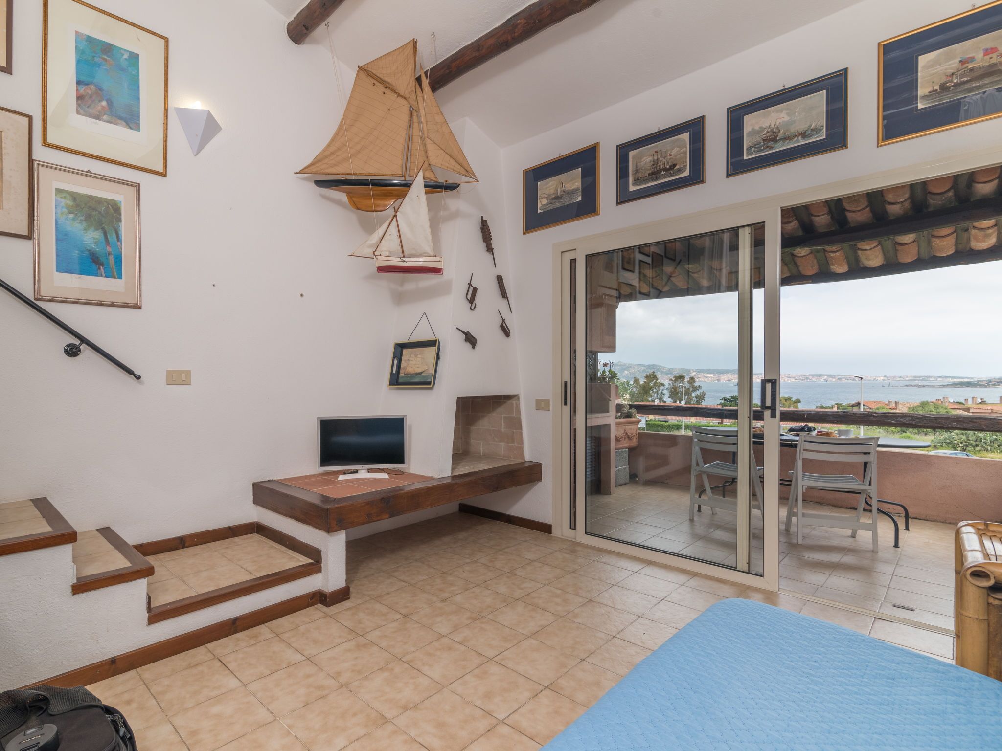 A room with a bed, a TV, a table, and a view of the sea.
