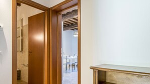 A hallway with a wooden door leading to a bathroom with a towel rack and a tiled floor. - Poggio di Nocola by Interhome (Riparbella)