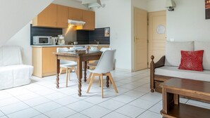 A modern kitchen with a dining area, a sofa, and a small table. - Odalys Référence Le Domaine des Rois by Interhome (Bergheim)