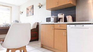 A modern kitchen with wooden cabinets, a white countertop, a microwave, a coffee maker, and a dishwasher. - Odalys Référence Le Domaine des Rois by Interhome (Bergheim)