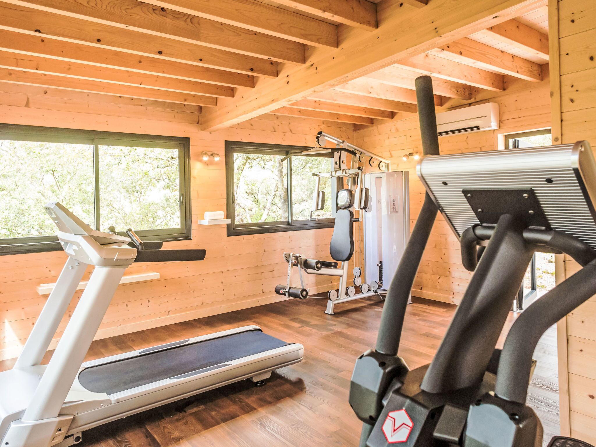 Ett gym med löpband, styrketräningsmaskiner och en vägg täckt med speglar.