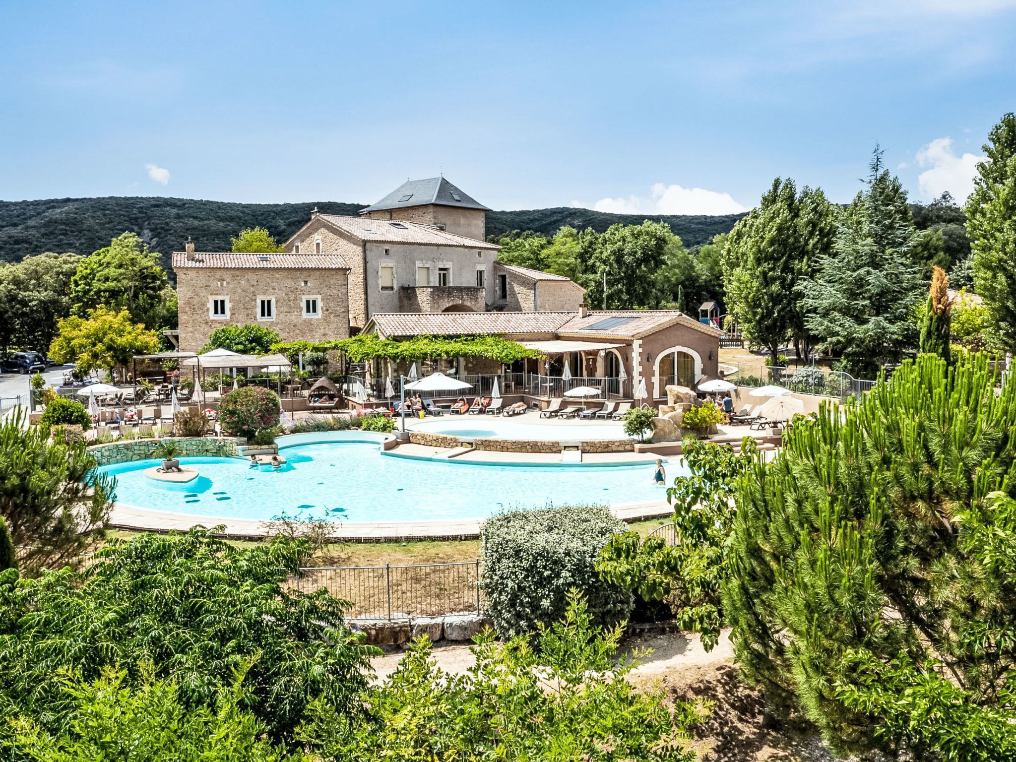 A resort with a swimming pool, outdoor seating, and a large building with a tower.
