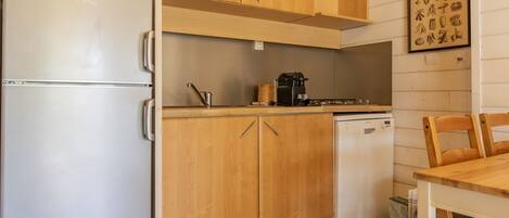 A compact kitchen with wooden cabinets, a built-in microwave, a coffee maker, and a dishwasher.