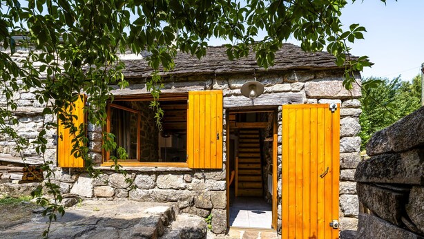 Ein Steinhaus mit Holzhörnern und einer Treppe, die zu einer oberen Ebene führt.
