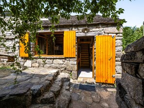 A stone building with wooden shutters and a staircase leading to an upper level. - Chassezac by Interhome (Les Vans)